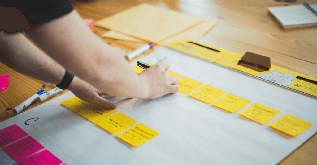 A guy updates the post-its of an agile kanban board during the definition of sprint goals